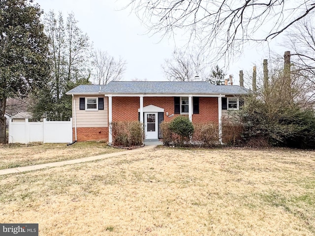 view of front of house featuring brick siding, a front yard, and fence