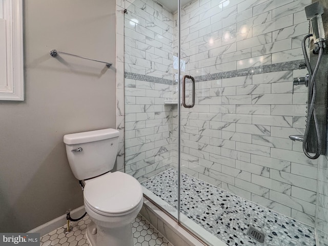 bathroom with tile patterned floors, a shower stall, toilet, and baseboards