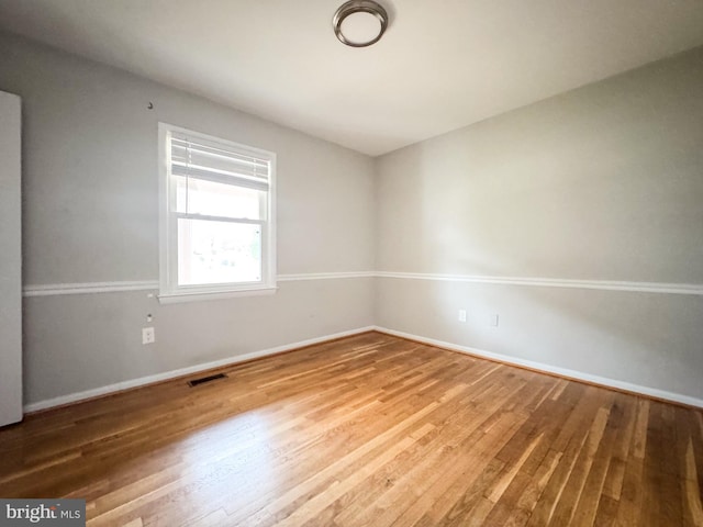 unfurnished room featuring visible vents, baseboards, and wood finished floors