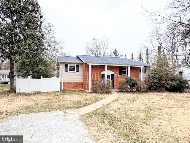 view of front of house with a front lawn, fence, and brick siding