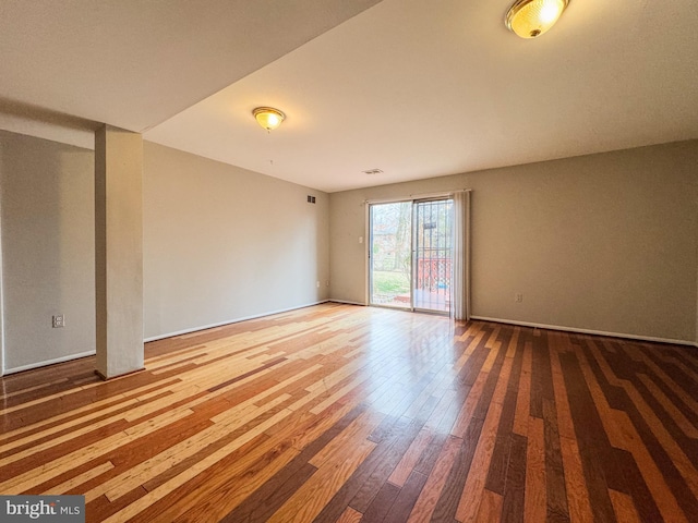 empty room with visible vents, baseboards, and hardwood / wood-style flooring