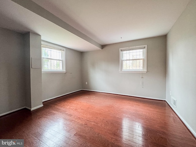 empty room with baseboards, visible vents, and wood-type flooring