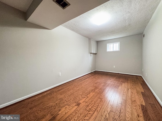 basement featuring wood finished floors, baseboards, and a textured ceiling