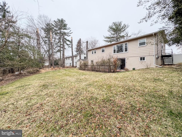 back of house with a lawn and fence