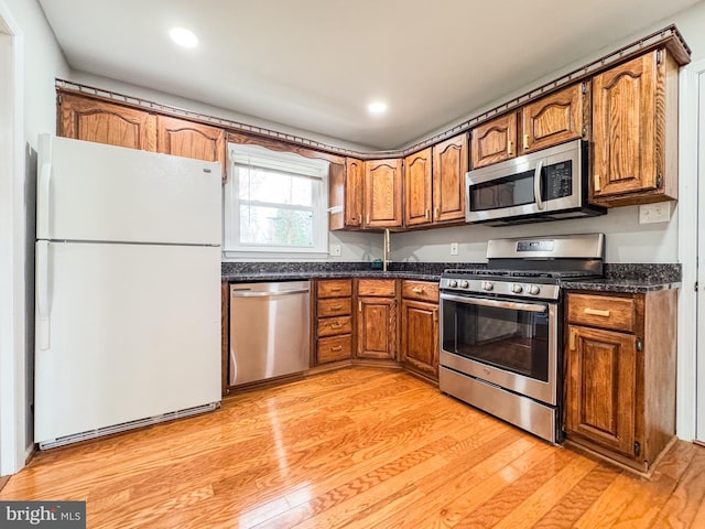 kitchen with brown cabinets, light wood-style floors, and appliances with stainless steel finishes