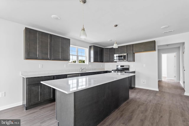 kitchen with a center island, decorative light fixtures, light countertops, wood finished floors, and stainless steel appliances