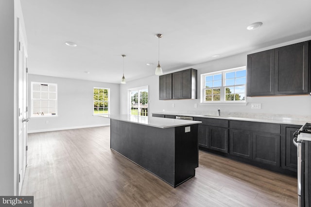 kitchen with a sink, wood finished floors, a center island, and light countertops