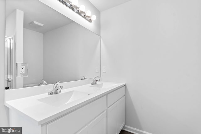 full bath with a sink, baseboards, and double vanity