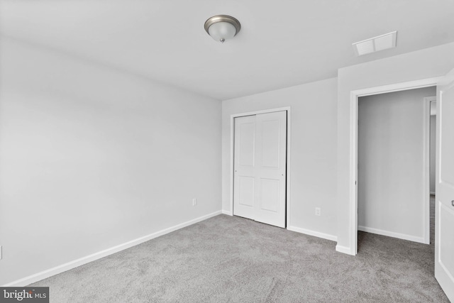 unfurnished bedroom featuring a closet, visible vents, baseboards, and carpet