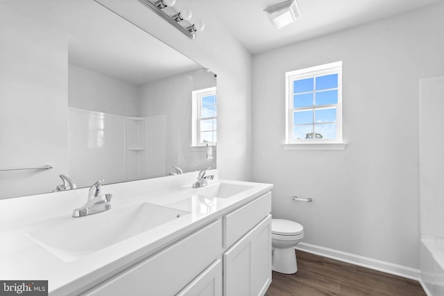 full bath with toilet, wood finished floors, visible vents, and a sink