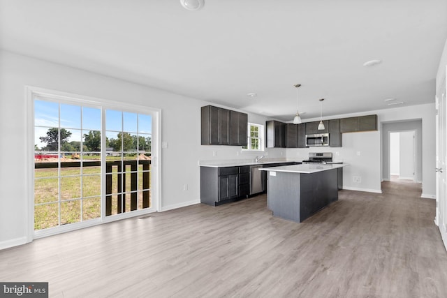 kitchen featuring light wood-type flooring, stainless steel appliances, a kitchen island, and light countertops