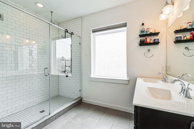 full bathroom featuring a shower stall, double vanity, baseboards, and a sink