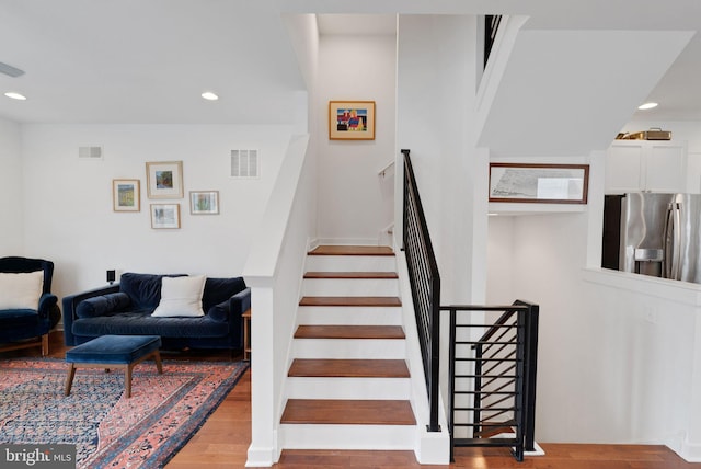 stairway with visible vents, recessed lighting, and wood finished floors