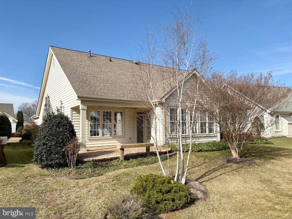 view of front facade with a front yard and roof with shingles