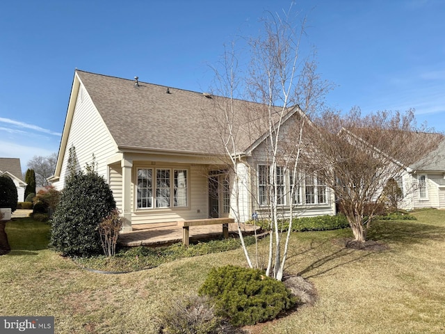 view of front facade with a front yard and roof with shingles