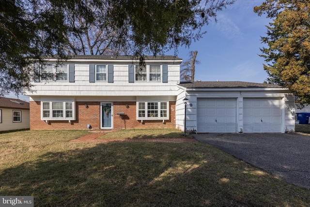 colonial home featuring brick siding, driveway, a front yard, and a garage