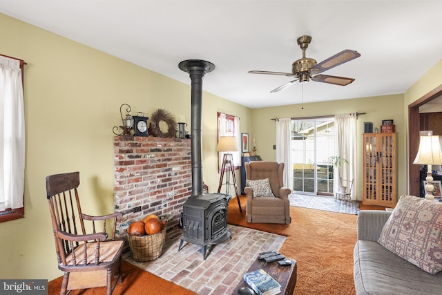 living area featuring a wood stove and ceiling fan