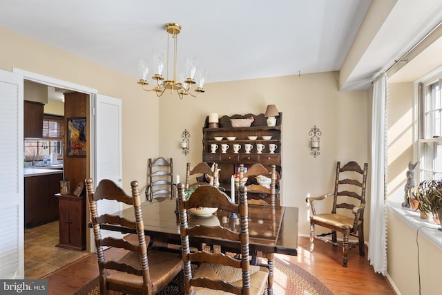 dining area with baseboards, wood finished floors, and a chandelier