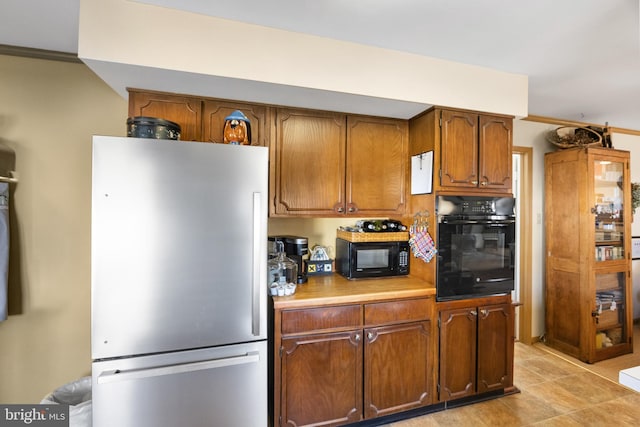 kitchen with black appliances, crown molding, brown cabinets, and light countertops