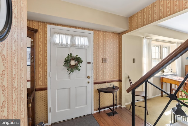 entrance foyer with wallpapered walls, visible vents, wood finished floors, and baseboards