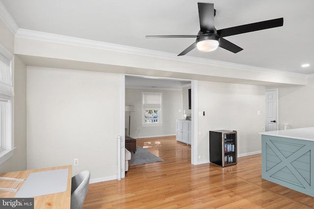 interior space with beverage cooler, crown molding, light wood-type flooring, and baseboards