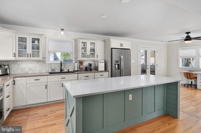 kitchen with light wood-type flooring, a sink, a center island, stainless steel appliances, and white cabinets