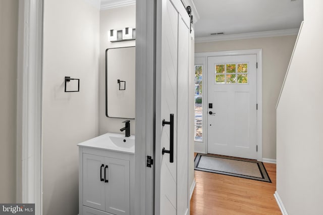 bathroom with visible vents, ornamental molding, wood finished floors, baseboards, and vanity