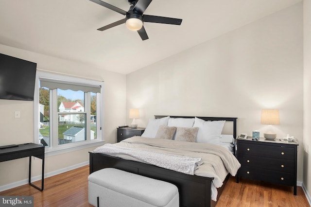 bedroom with vaulted ceiling, wood finished floors, baseboards, and ceiling fan