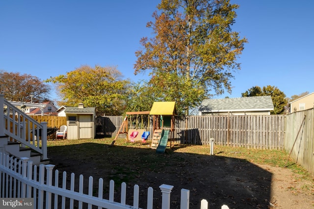 view of yard featuring a storage unit, an outbuilding, a fenced backyard, and a playground