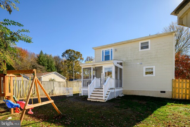 rear view of property featuring a playground, a fenced backyard, a sunroom, and crawl space