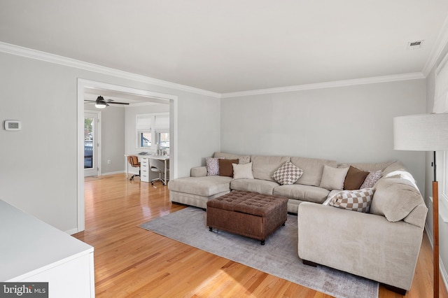 living room featuring crown molding, baseboards, visible vents, and light wood finished floors