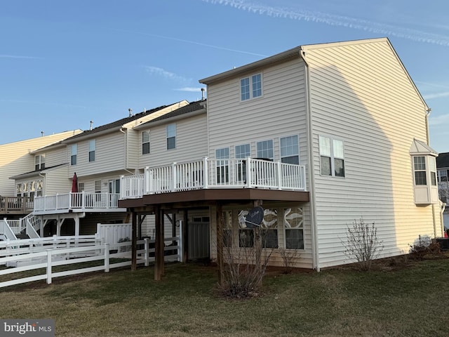 rear view of house featuring a deck, a yard, and fence