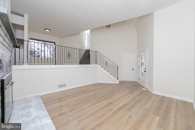 interior space featuring visible vents, wood finished floors, stairway, a high ceiling, and a fireplace