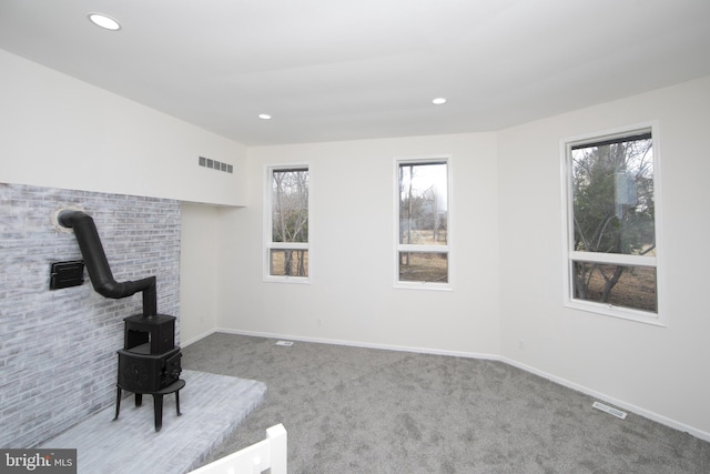 unfurnished living room featuring a wealth of natural light, visible vents, and carpet