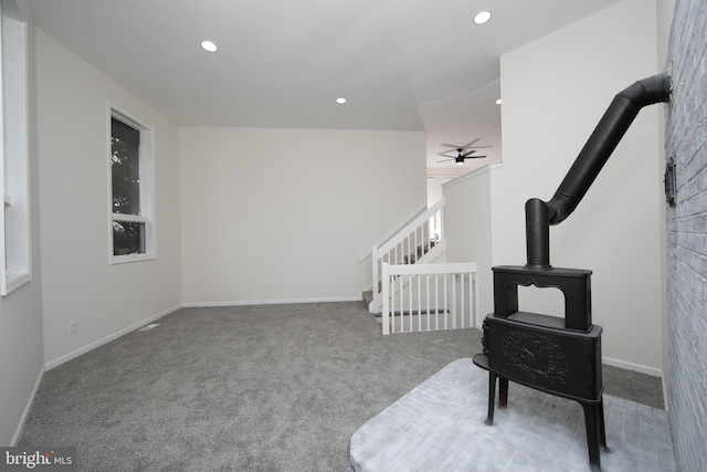 sitting room featuring recessed lighting, carpet floors, baseboards, ceiling fan, and a wood stove