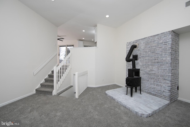 unfurnished living room featuring visible vents, carpet floors, baseboards, a wood stove, and recessed lighting