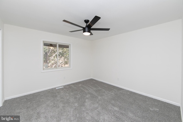 unfurnished room with dark colored carpet, visible vents, baseboards, and ceiling fan