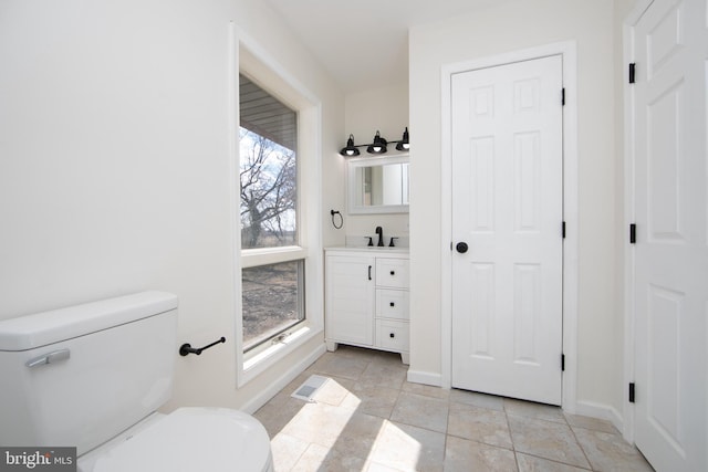 bathroom featuring baseboards, toilet, vanity, and tile patterned flooring