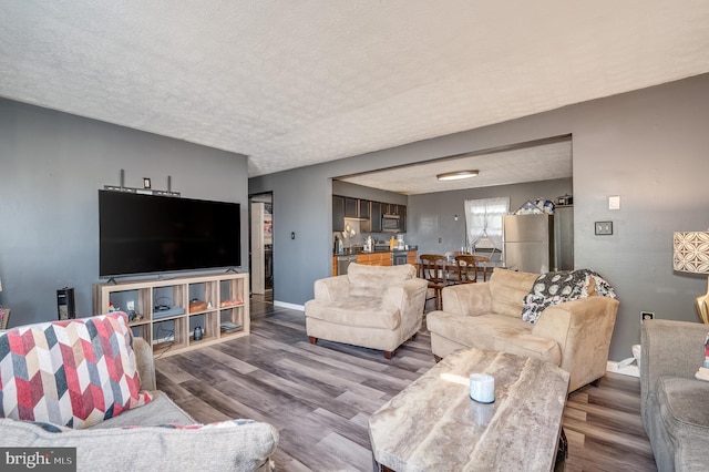 living room featuring a textured ceiling, baseboards, and wood finished floors