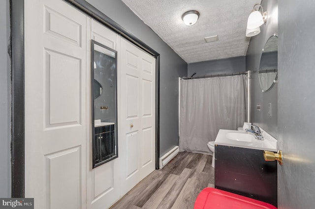 full bathroom with vanity, a shower with curtain, wood finished floors, a textured ceiling, and a baseboard radiator