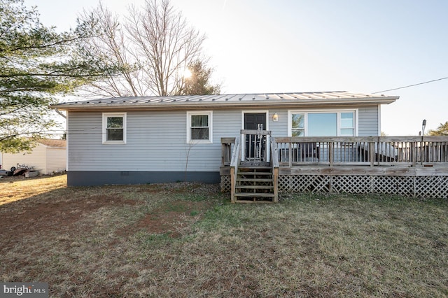 rear view of property featuring a wooden deck, metal roof, a yard, crawl space, and a standing seam roof