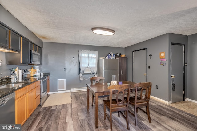 dining space with a baseboard heating unit, baseboards, dark wood-type flooring, and a textured ceiling