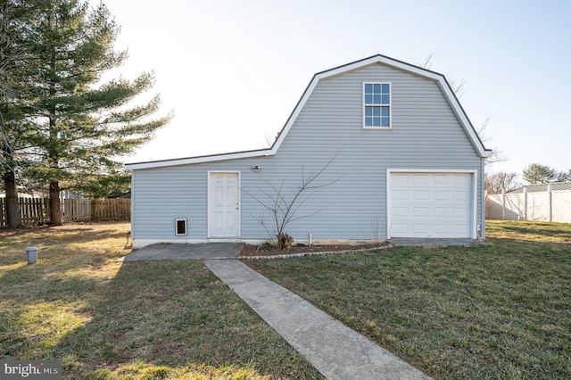 back of house with a gambrel roof, a lawn, a garage, and fence