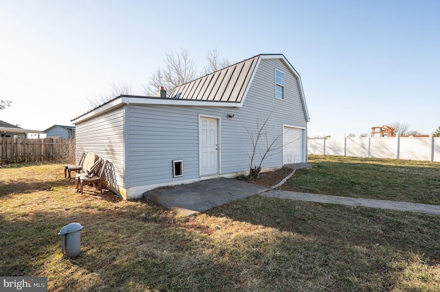 exterior space featuring a gambrel roof, a lawn, fence, a garage, and a chimney