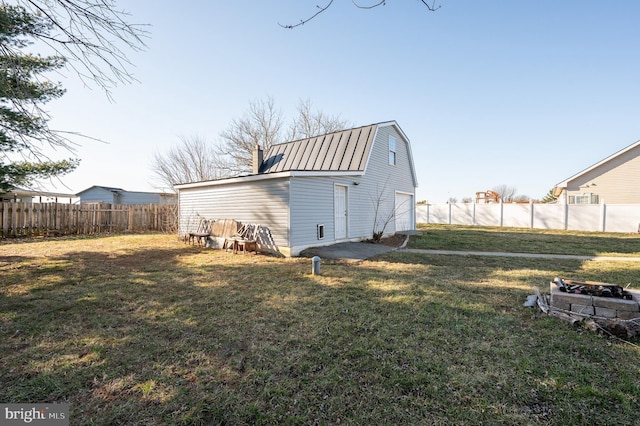 exterior space with fence, a gambrel roof, metal roof, a yard, and an outbuilding