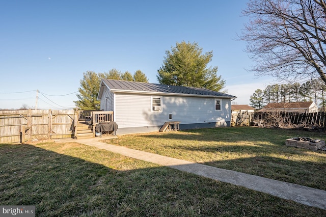 back of property featuring metal roof, a fire pit, a fenced backyard, and a yard