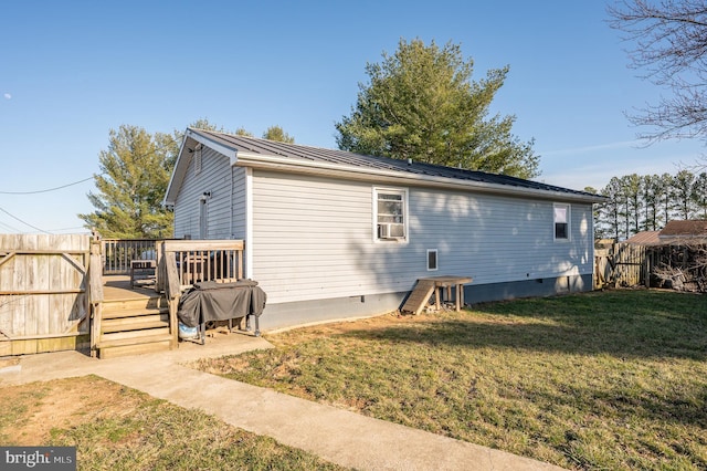 rear view of property with fence, a yard, crawl space, a deck, and metal roof