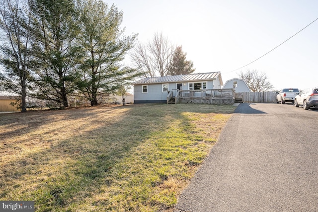 view of front of home with a deck, a front lawn, a standing seam roof, aphalt driveway, and metal roof