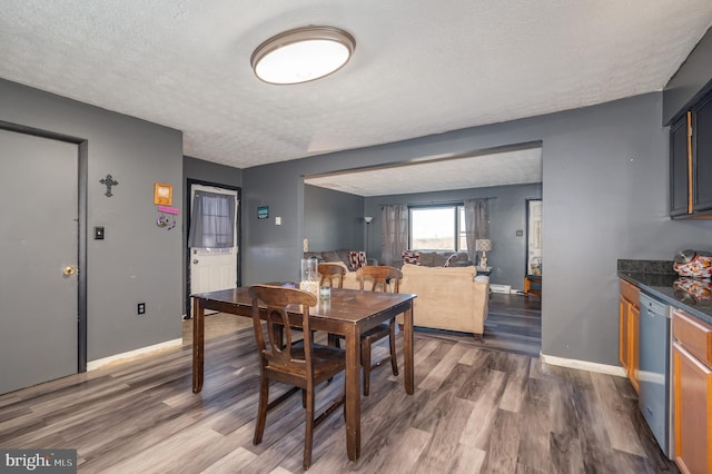 dining area with baseboards, a textured ceiling, and wood finished floors