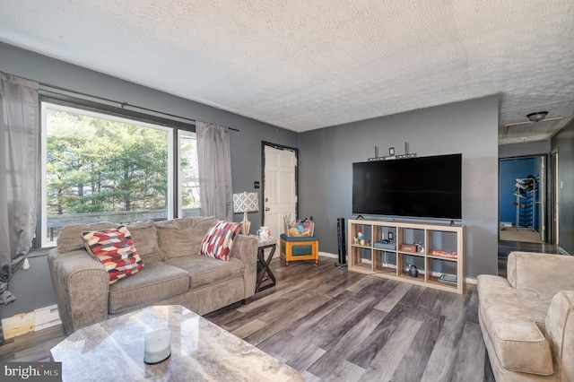 living area featuring baseboard heating, a textured ceiling, baseboards, and wood finished floors